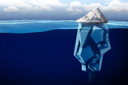 Small top of iceberg above surface of water with a much larger portion beneath the surface