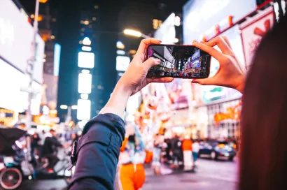 Woman holding phone up to take a picture in Times Square, NYC